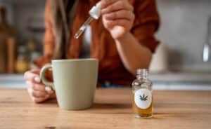 Woman pouring cannabis oil into her tea at home