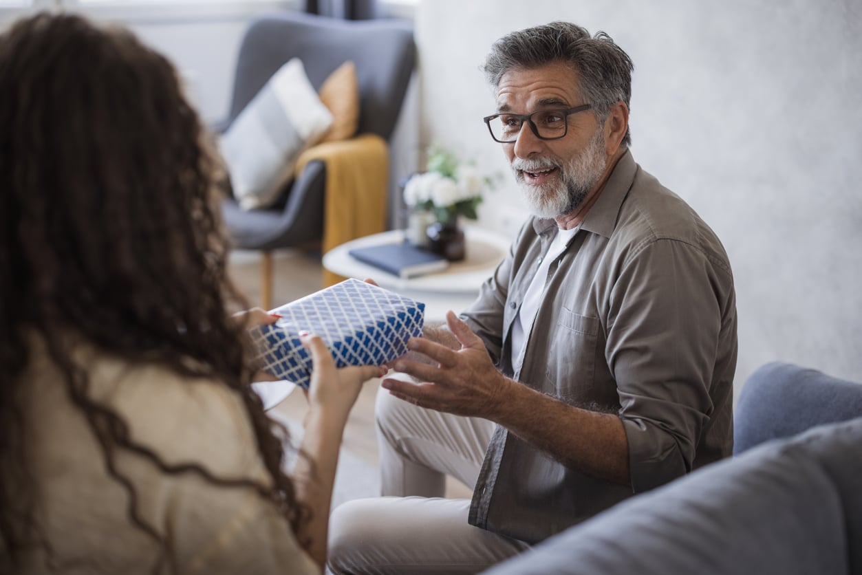 Daughter surprising her father with a gift in the living room